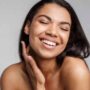 Dunkelhäutige Frau mit glatter und schöner haut lächelt in die Kamera